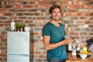 Young man standing in kitchen on mobile phone